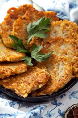 Patates Latkeler geleneksel Yahudi krep ekşi krema, maydanoz, kuru kırmızı pul biber ve nane sosu ile. Arka plan, beyaz mavi çiçekli peçete. Hannukah kutlama yemeği kavramı. Yakın çekim.