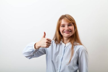 Casual mavi gömlek gülümseyen ve hevesli ve kaliteli memnun başparmak biraz duygu gösterilen güzel kızıl saçlı Bayan portresi Studio giymiş 