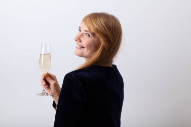 Kızıl saçlı ve çilli şampanya tutarak ve gülümseyen koyu elbiseli genç zarif Bayan yarı açık 