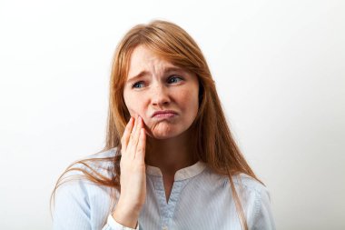 yanakları dokunmaktan ve üzgün yüz ifadesi, diş ağrısı kavramı ile kameraya bakıyor güzel ve komik Kızıl saçlı kadın 