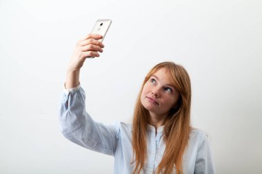 Kızıl saçlı ve çilli telefon tutarak ve selfie yapmak ile Avrupa genç bayan 