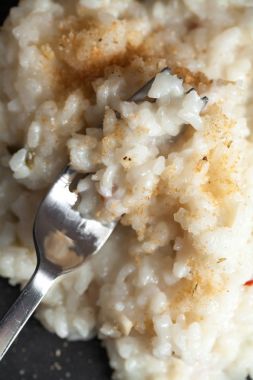 ahşap masa üzerinde siyah seramik plaka baharatlı ekmek kırıntıları ile geleneksel krem ihale risotto 