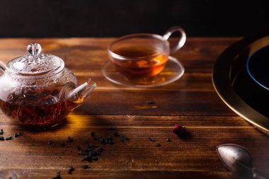 siyah çay ve altın tepsi ahşap masa üzerinde kupa ile cam çaydanlık 