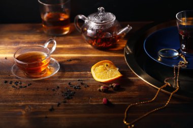 küçük cam çaydanlık sıcak siyah çay ve sıkılmış portakal dilimi ve ahşap zemin, Doğu çay zaman kavramı üzerine altın tepsi 