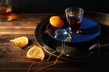 zincir üzerinde altın Büyüteç'i ve ahşap masa sıkılmış portakal dilimleri ile mavi plaka üzerinde siyah Türk çayı ile cam 