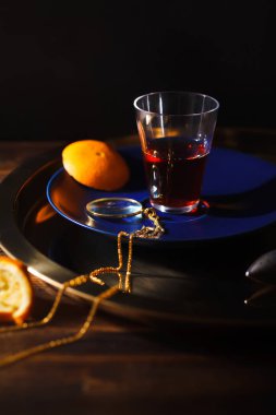 zincir üzerinde altın Büyüteç'i ve ahşap masa sıkılmış portakal dilimleri ile mavi plaka üzerinde siyah Türk çayı ile cam 