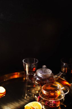 küçük cam çaydanlık ve bardak sıcak siyah çay ve altın tepsi sıkılmış portakal dilimleri ile kurutulmuş gül yaprakları 