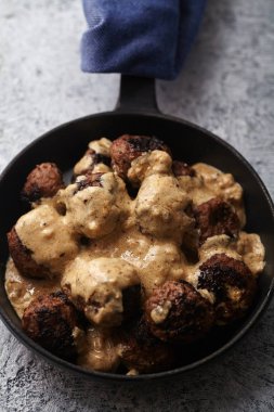 Mavi havlu sarma kolu ile bölümü siyah dökme demir tavada geleneksel İsveç sığır eti köfte et suyu ile servis 