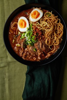 domuz yağı ile Japon ramen ve yeşil keten masa örtüsü üzerinde marine edilmiş yumurtalı mantar ile kase