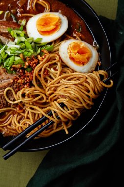 domuz yağı ile Japon ramen ve mantarlı yumurta üzerinde yeşil keten masa örtüsü ile kase
