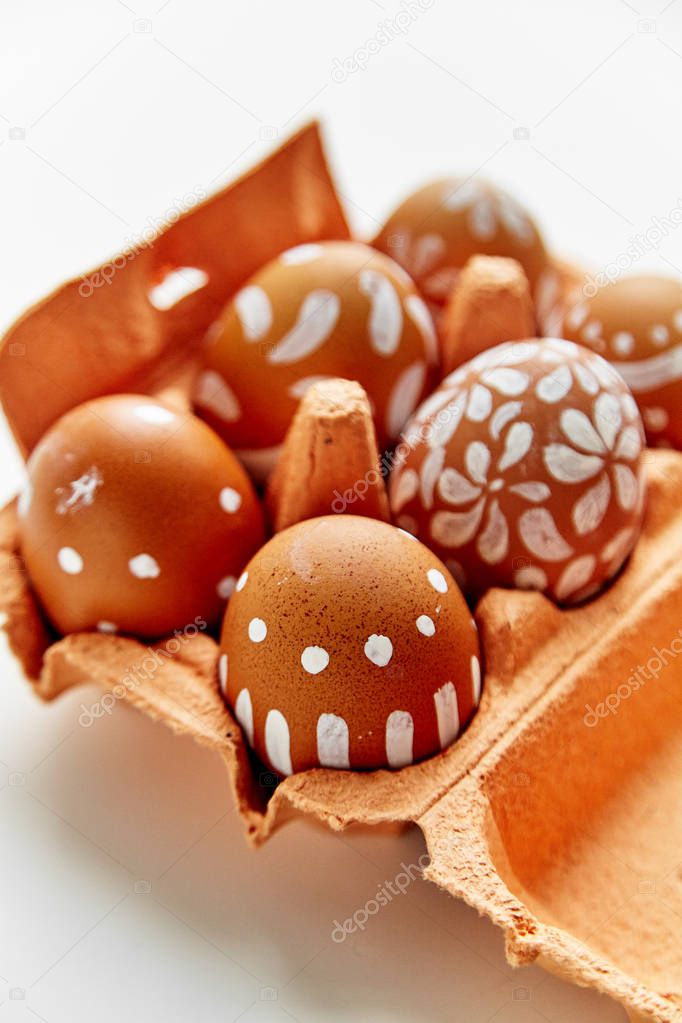 painted eggs in various white patterns in colorful orange cardboard container, Easter holiday concept 