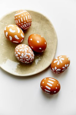 Beyaz arka plan üzerinde Paskalya tatil kavramı izole çeşitli desenler ile beyaz boyalı yumurta ile plaka 