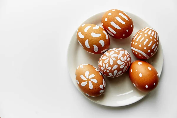 plate with white painted eggs with various patterns isolated on white background, Easter holiday concept