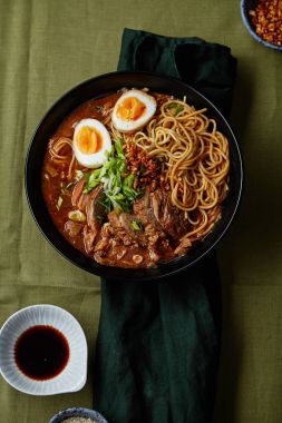 domuz yağı ile Japon ramen ve mantarlı yumurta üzerinde yeşil keten masa örtüsü ile kase