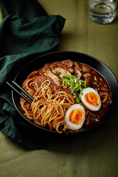 domuz yağı ile Japon ramen ve mantarlı yumurta üzerinde yeşil keten masa örtüsü ile kase