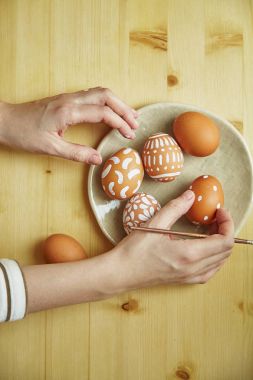 eller fırça ve yumurta çeşitli beyaz desenler ile boyalı yumurta ile tablo üzerinde Paskalya tatili plaka üzerinde basılı       