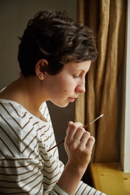 çizgili gömlekli fırça boya yumurta Paskalya tatilde, eski gelenekleri kavram sadeliği tutarak siyah kısa saçlı genç kadın modeli giymiş 