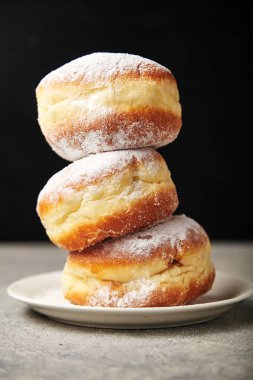 stack of donuts with powdered sugar on white plate  clipart