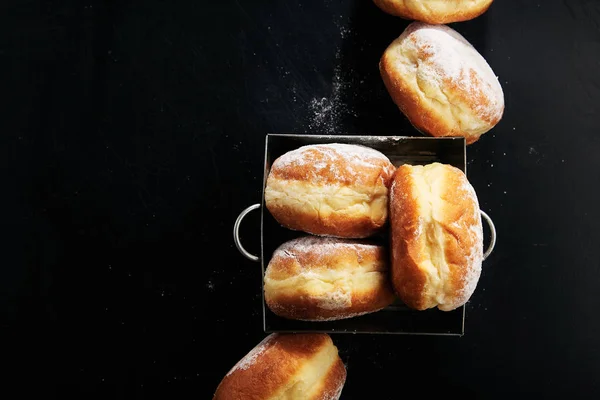 donuts with powdered sugar in metal box , close-up