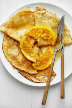 Beyaz tabak krep ve ahşap masa üzerinde turuncu lezzetli  