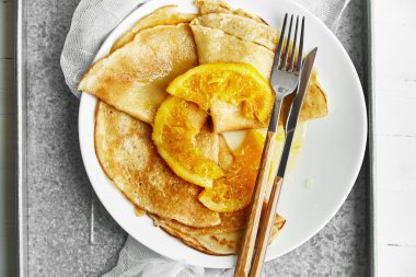 ahşap masa üzerinde metalik tepsi üzerinde beyaz tabak içinde portakal lezzetli ile Pancakes 