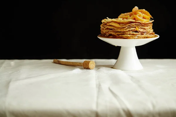 crepes cake with orange jam and honey on white cake stand, pancake breakfast concept