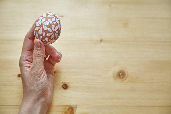 female hand holding egg over wooden table, Easter holiday concept 