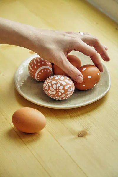 Женская Рука Берет Яйцо Тарелки Окрашенными Яйцами Различными Белыми Узорами — стоковое фото