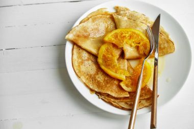 Beyaz tabak krep ve ahşap masa üzerinde turuncu lezzetli  