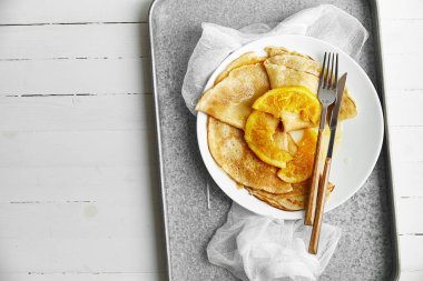 ahşap masa üzerinde metalik tepsi üzerinde beyaz tabak içinde portakal lezzetli ile Pancakes 