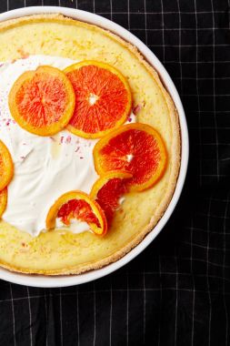 Cheesecake karamelize kırmızı portakal ve koyu zemin üzerine krem şanti ile yakın çekim 