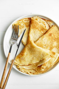 Krep çatal ve bıçak ahşap masa üzerinde beyaz plaka üzerinde 