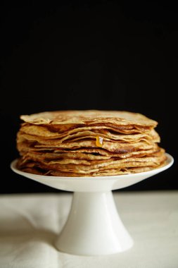 Krep pasta ve bal koyu arka plan, tablo ile portakal reçeli ile beyaz pasta stand yakın çekim 