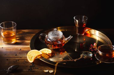 sıcak siyah çay çaydanlık ve Kupası ile cep Büyüteç ahşap zemin üzerine altın tepsi  