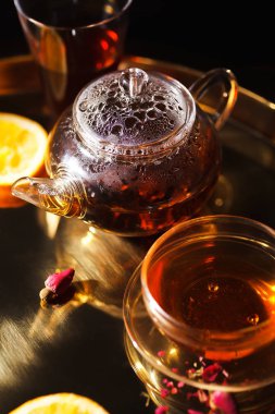 küçük cam çaydanlık ve bardak sıcak siyah çay ve altın tepsi sıkılmış portakal dilimleri ile kurutulmuş gül yaprakları 