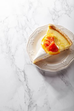 yumuşak cheesecake ile dilim kırmızı portakal karamelize ve beyaz mermer masa tabakta servis krem şanti 