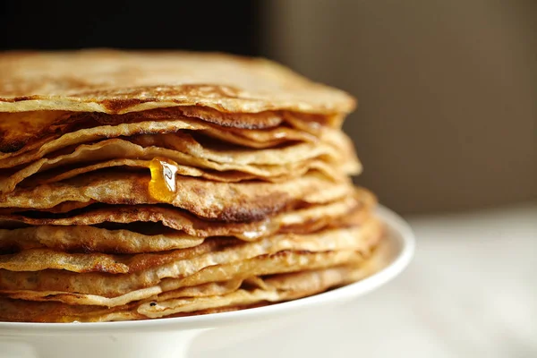 white cake stand with crepes cake and orange jam with honey on table with dark background, close-up