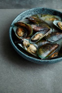 kivi midye marnier ve maydanoz el yapımı mavi seramik plaka gri arka plan üzerinde beyaz şarap soslu pişmiş 