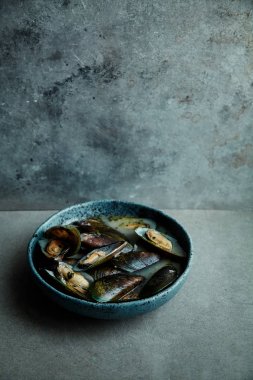 kivi midye marnier ve maydanoz el yapımı mavi seramik plaka gri arka plan üzerinde beyaz şarap soslu pişmiş 