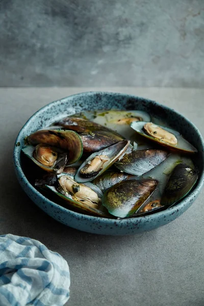 kivi midye marnier ve maydanoz el yapımı mavi seramik plaka gri arka plan üzerinde beyaz şarap soslu pişmiş 