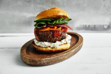 ızgara sığır patty krem peynir ve ıspanak üzerinde klasik topuz ile burger ile ahşap plaka 