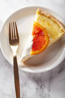 yumuşak cheesecake ile dilim kırmızı portakal karamelize ve beyaz mermer masa tabakta servis krem şanti 