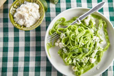 geleneksel İtalyan el yapımı ıspanak tagliatelle ve ricotta peynirli yeşil kareli masa örtüsü ile plaka