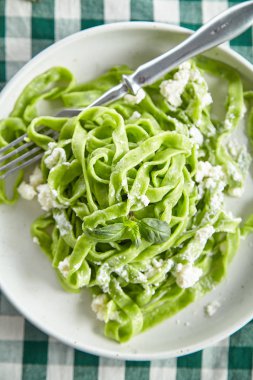geleneksel İtalyan el yapımı ıspanak tagliatelle ve ricotta peynirli yeşil kareli masa örtüsü ile plaka