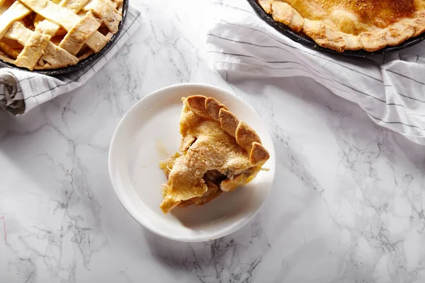 cooked apple pies with slice on plate on white marble table