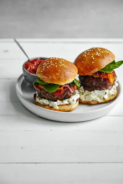 white ceramic plate with burgers and sauce in bowl on wooden table, close-up