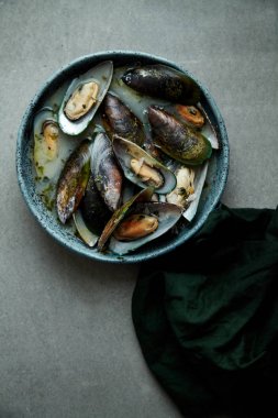 kivi midye marnier ve maydanoz el yapımı mavi seramik plaka gri arka plan üzerinde beyaz şarap soslu pişmiş 