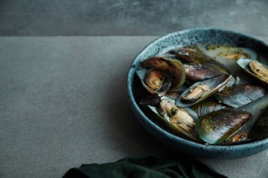 kivi midye marnier ve maydanoz el yapımı mavi seramik plaka gri arka plan üzerinde beyaz şarap soslu pişmiş 