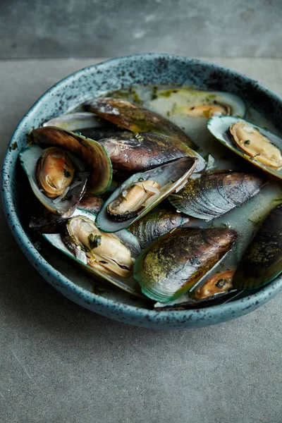 kivi midye marnier ve maydanoz el yapımı mavi seramik plaka gri arka plan üzerinde beyaz şarap soslu pişmiş 