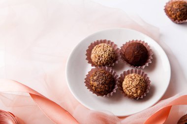 çeşitli çikolatalar ve beyaz arka plan üzerinde şeffaf kumaş ile pembe ipek kurdele ile plaka 